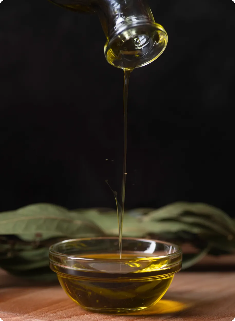 Pouring golden oil into a glass bowl, symbolizing purity and health.