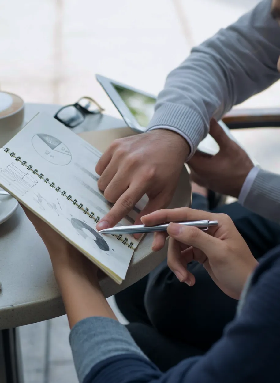 Close-up of two people reviewing data and sketches in a notebook