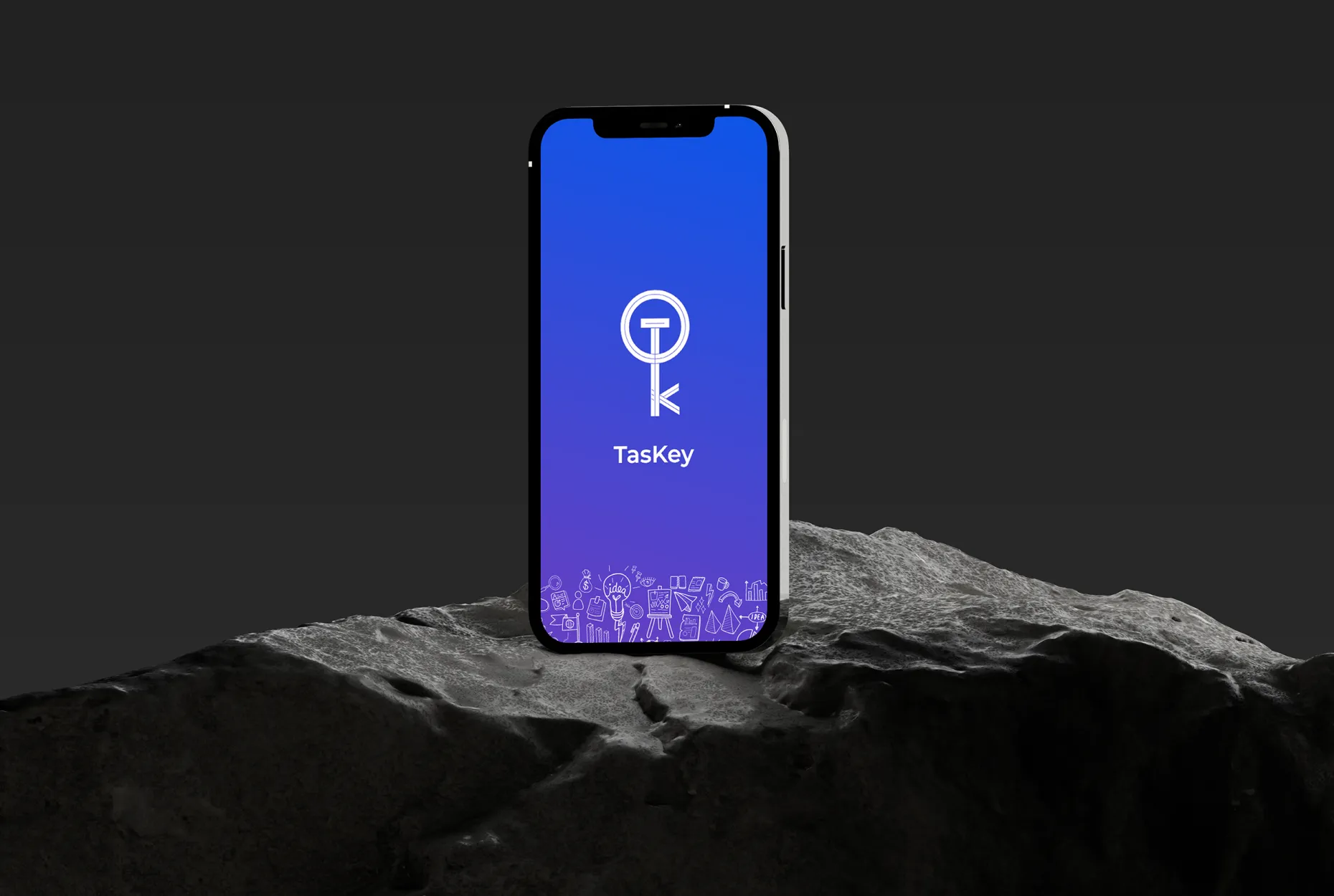 Smartphone displaying the TasKey app logo on a blue screen, placed on a rocky surface.